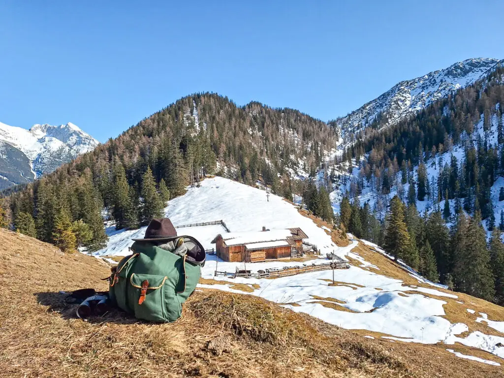 Jägerrucksack und Fernglas auf schneebedeckter Alm im Revier Giessenbach Tirol